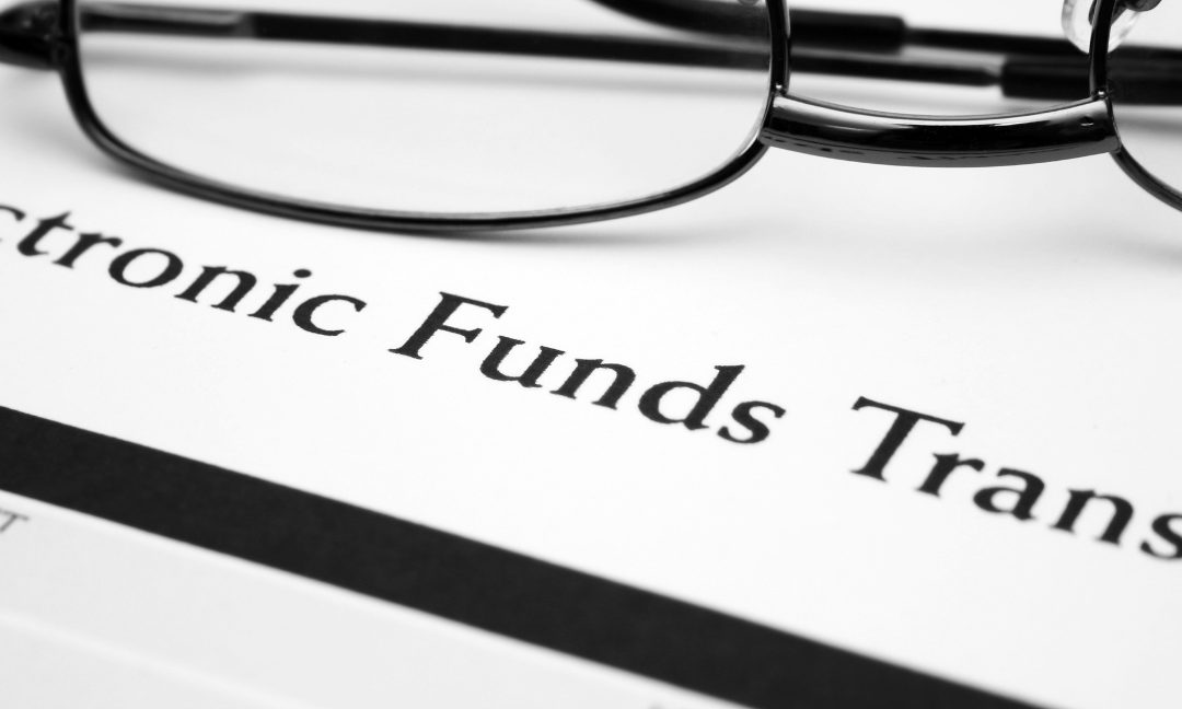 A pair of glasses on top of an electronic funds transfer paper | Why Transition to ACH EFT?