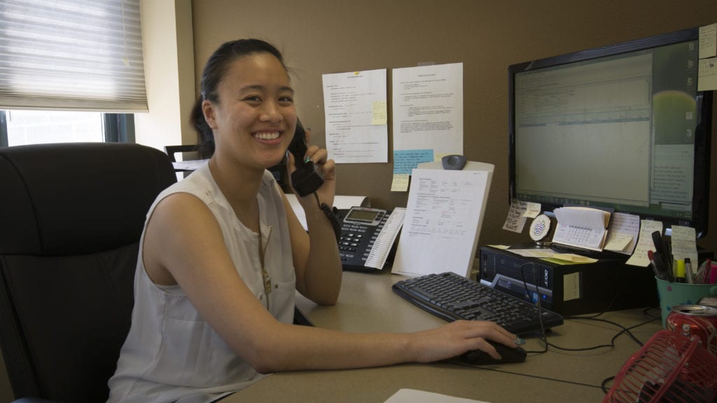 Smiling woman on the phone at her desk to illustrate what is medical billing.