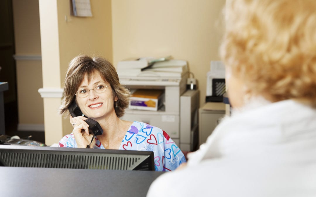 A receptionist greets a guest to illustrate the blog post 5 Unethical Medical Billing Practices