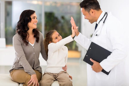 A doctor high-fiving a young girl as her mother looks on to illustrate patient management through Medical IT Services.